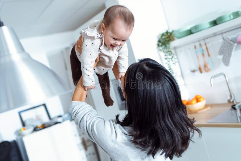 Happy young mother lifting her cute daughter up high in air while spending and enjoying time together at home royalty free stock image Happy young mother lifting her cute daughter up high in air while spending and enjoying time together at home royalty free stock image