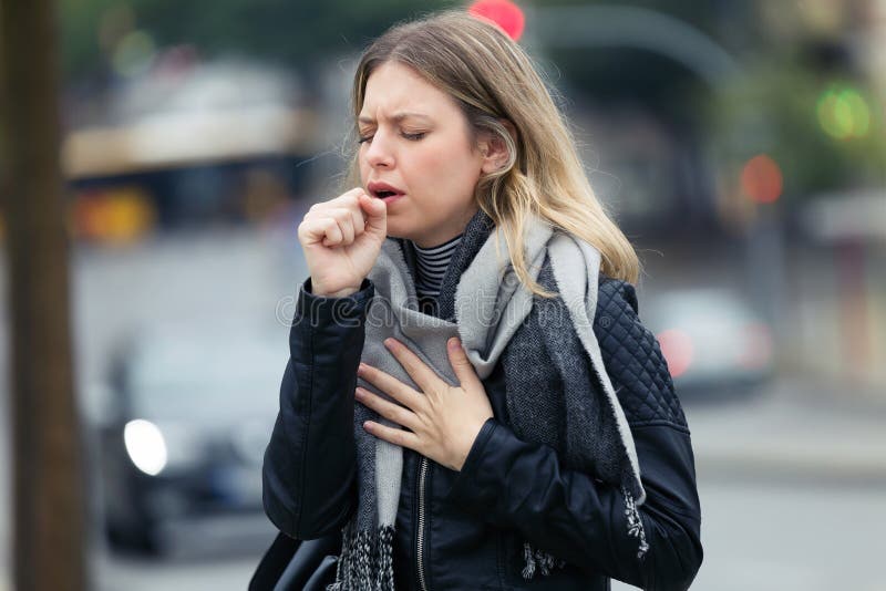Illness young woman coughing in the street royalty free stock photography Illness young woman coughing in the street royalty free stock photography