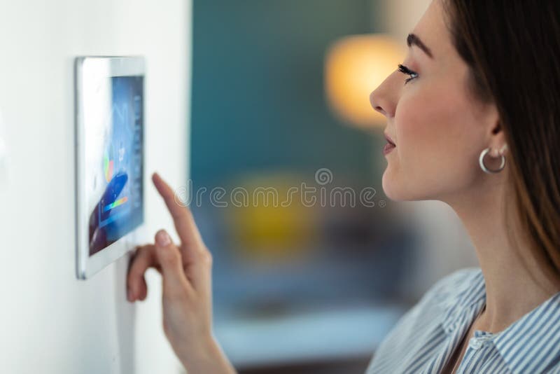 Pretty young woman using the home automation system on digital tablet to regulate the temperature