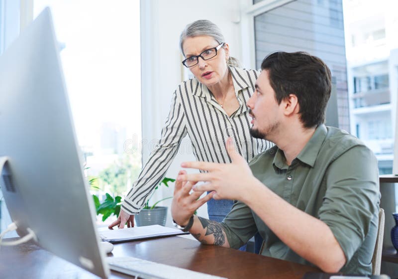 Creating something innovative together. Shot of two businesspeople working together on a computer in an office. stock images