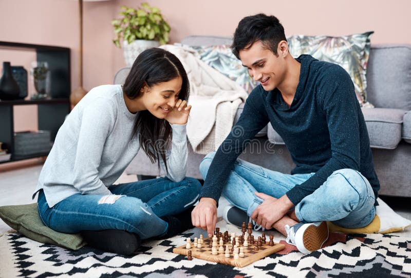 young couple playing chess while sitting at table at home - Unpacked