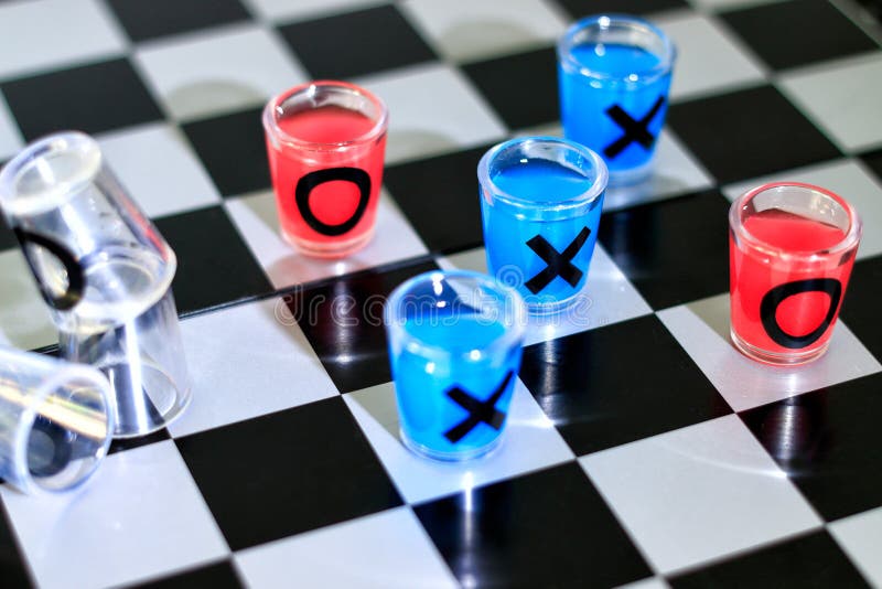 Focused man sipping alcoholic beverage while thinking about next chess move.  Stock Photo by DC_Studio