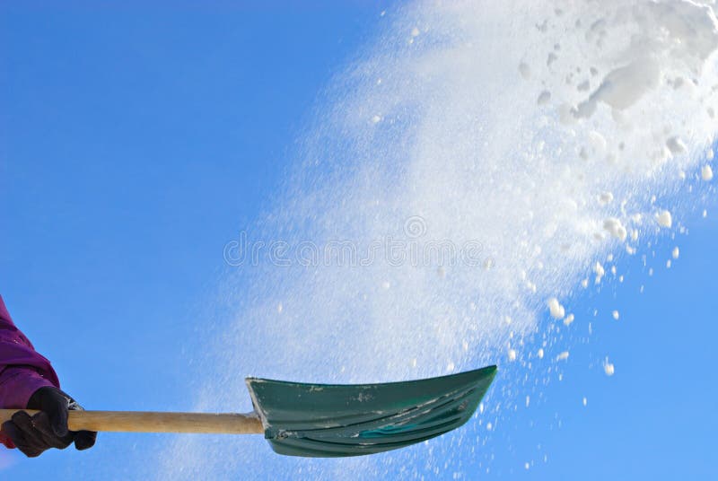 Snow shovel throwing snow in the air against blue sky. Snow shovel throwing snow in the air against blue sky