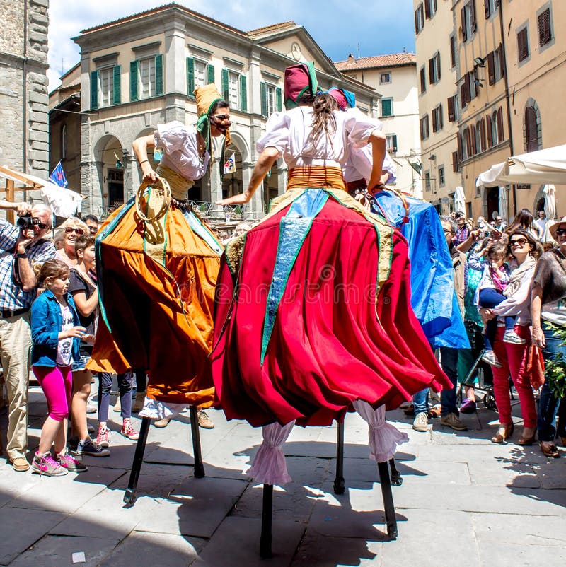 Show of stilt walkers in the street. CORTONA - iTALY - JUNE 01, 2014: show of stilt walkers in the street surrounded by the spectators Show of stilt walkers in the street. CORTONA - iTALY - JUNE 01, 2014: show of stilt walkers in the street surrounded by the spectators