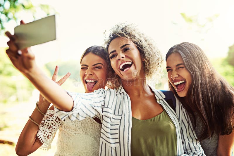 Smiling teenage girl taking selfie with friends while sitting on steps in  city stock photo