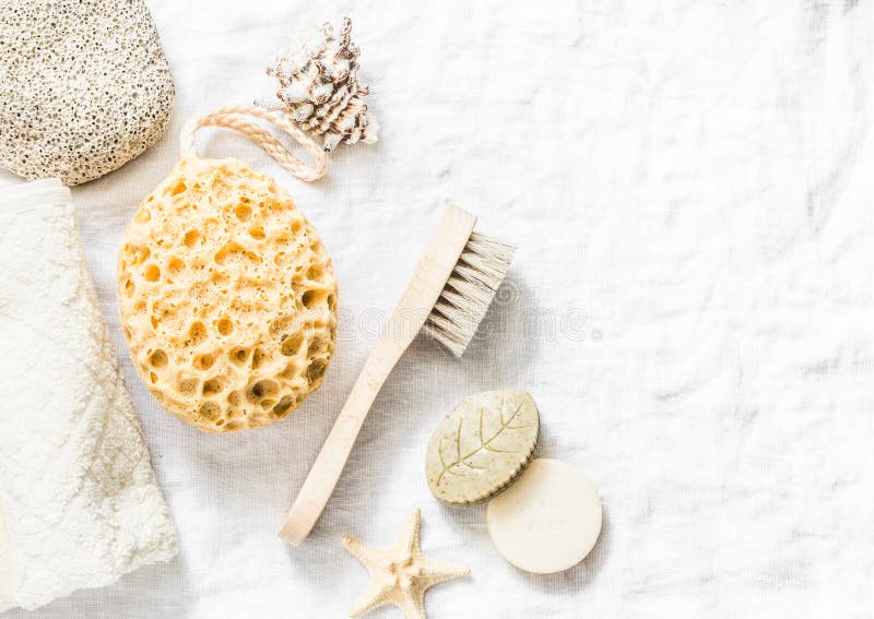 Shower accessories - face brush, sponge, pumice stone, towel, soap on a light background, top view. Cleansing of the skin health c