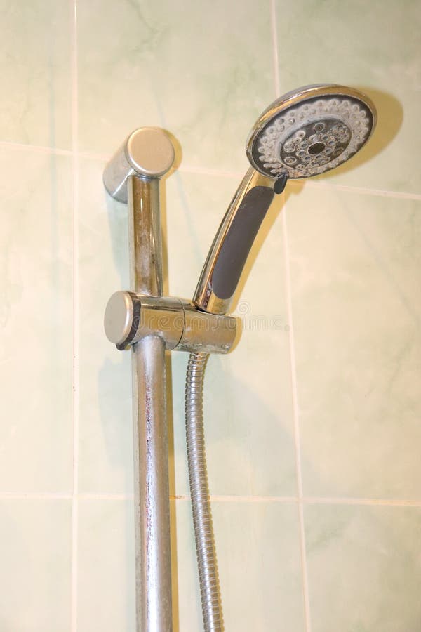 Shower head with limescale in the holder on the bathroom wall stock photos
