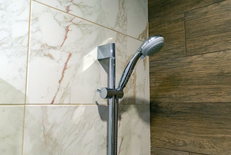 Shower Head on the Wall of Ceramic Tiles in the Bathroom Stock Photo