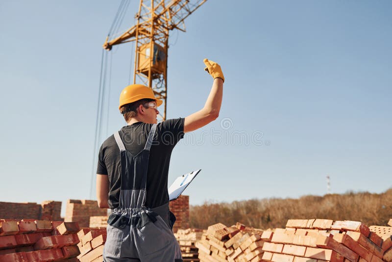 Shows Gestures and Talks. Construction Worker in Uniform and Safety
