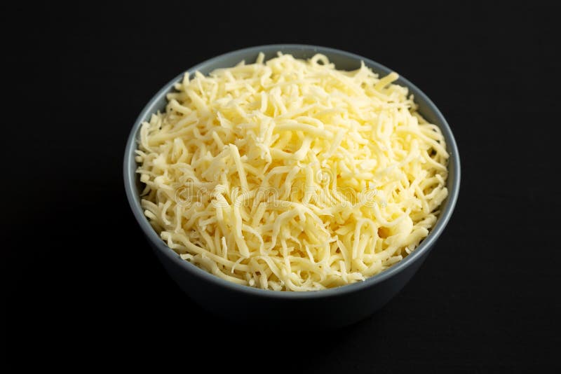 Shredded Mozzarella Cheese in a Bowl on a Black Surface, Side View