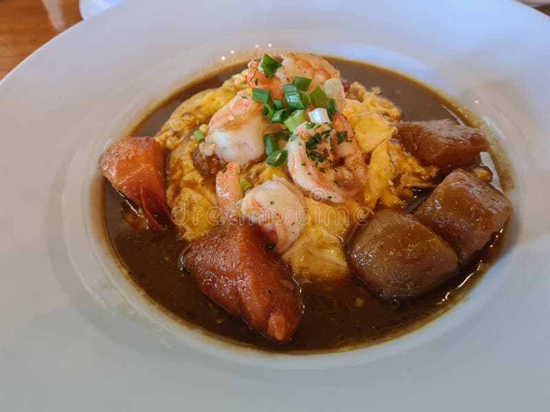 Shrimp in curry sauce with rice and coriander closeup on plate.