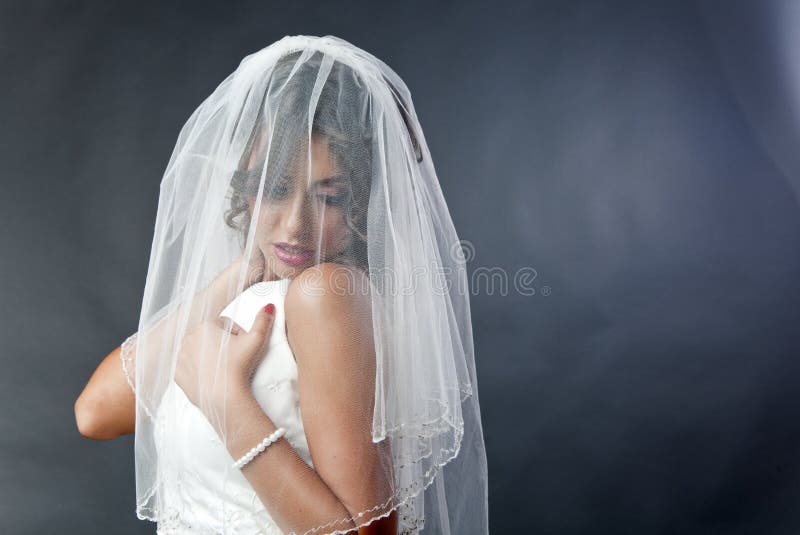 Young shy bride with white wedding dress and veil over her face. Young shy bride with white wedding dress and veil over her face