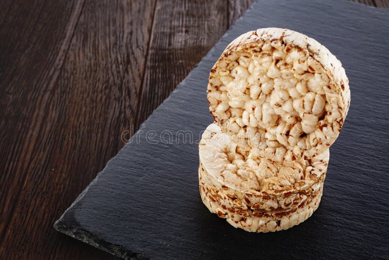 Sia a dieta il mucchio dei dolci di riso sul pezzo scuro di bordo sulla tavola di legno, fuoco selettivo fotografie stock libere da diritti Sia a dieta il mucchio dei dolci di riso sul pezzo scuro di bordo sulla tavola di legno, fuoco selettivo fotografie stock libere da diritti