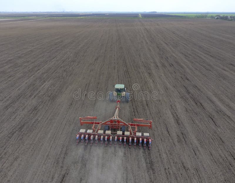 Sowing of corn. Tractor with a seeder on the field. Using a seeder for planting corn. Sowing of corn. Tractor with a seeder on the field. Using a seeder for planting corn