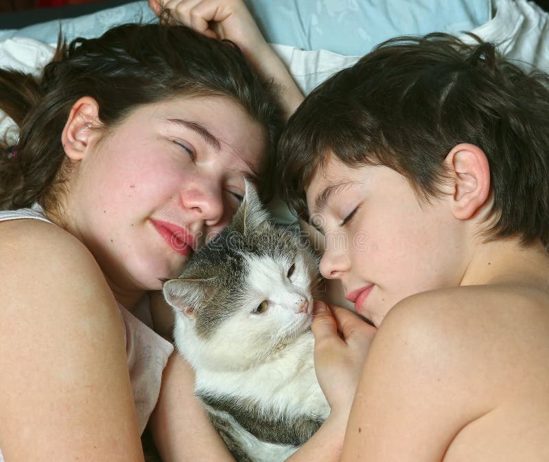 Siblings kids brother and sister sleep with cat. 