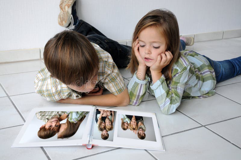 Hermanos acostada sobre el piso a buscando familia fotografías.