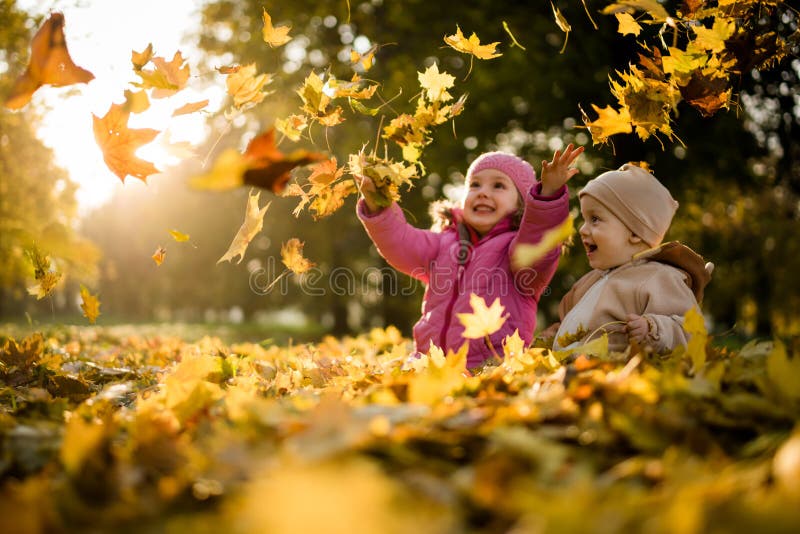 Kids having fun in park, throwing up leaves.