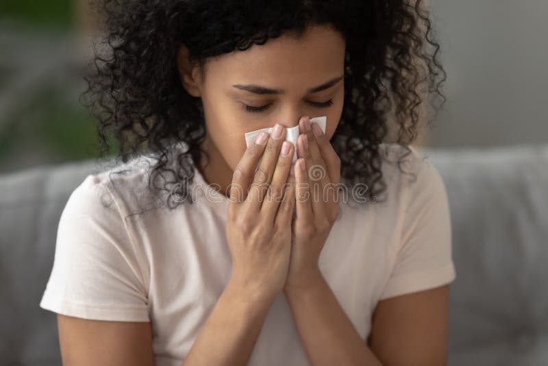 Sick african American woman blowing nose having rhinitis