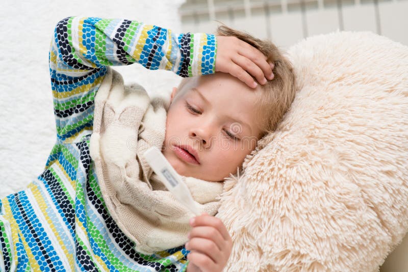 Sick Boy with Thermometer Laying in Bed and Taking Temperature Stock