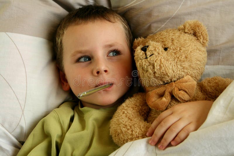 Bambino con il termometro e dolce orsacchiotto di peluche giaceva a letto con l'influenza e la febbre.