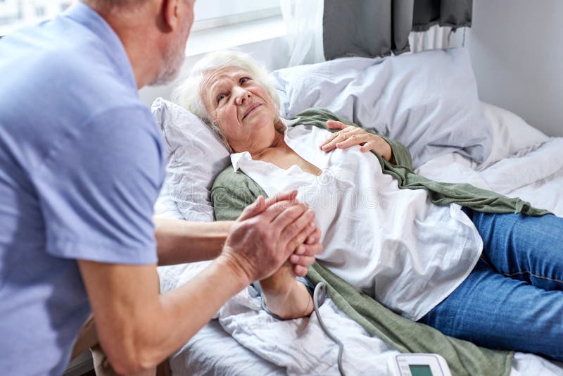 sick female patient at hospital with worried husband holding hands stock photography