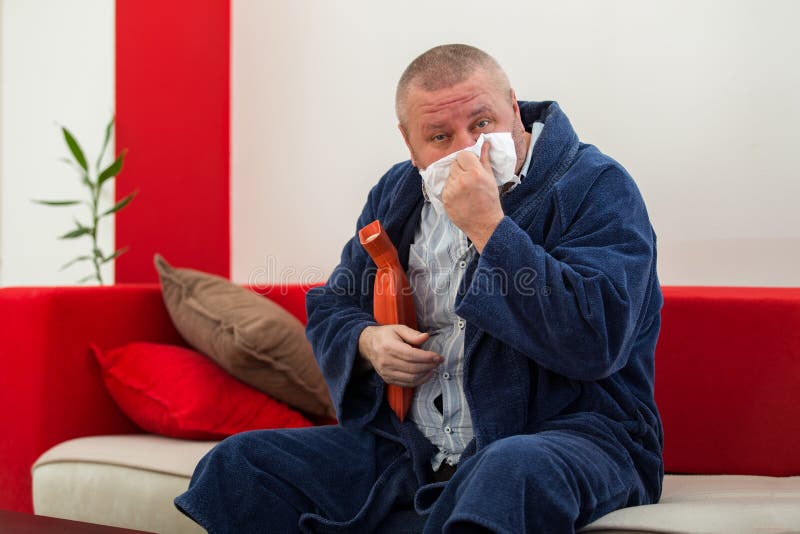 Sick Man in Bed Having a Headache Holding a Hotwater Bottle Stock