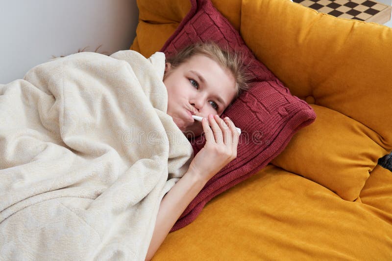 Sick preteen girl laying in bed using thermometer royalty free stock images