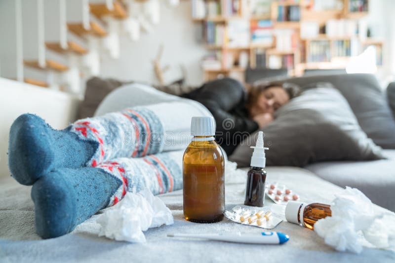 Sick woman with flu, cold, fever or virus sitting on sofa at home