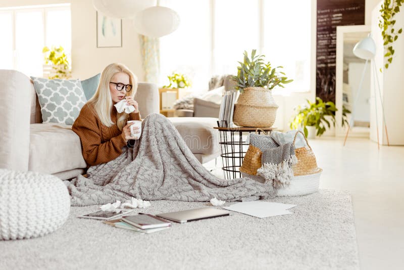 Sick woman sitting on floor covered with a blanket and blowing n royalty free stock photos Sick woman sitting on floor covered with a blanket and blowing n royalty free stock photos