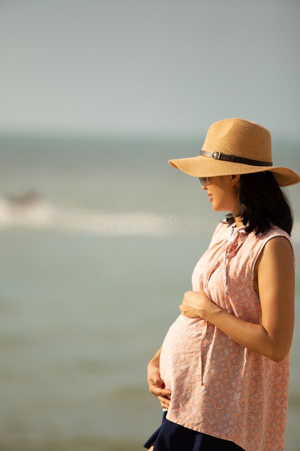 Sida av vacker gravid kvinna på stranden.