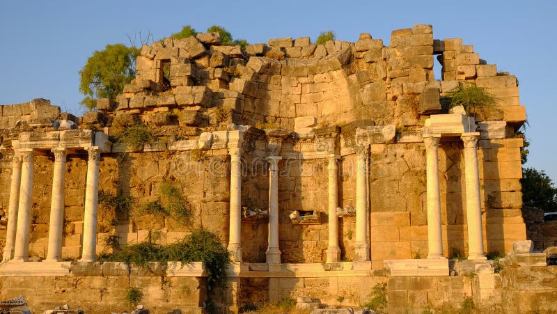 SIDA TURKIET - JULI 5, 2019: Den monumentala springbrunnen Nymphaeum i antik sidostad royaltyfria bilder SIDA TURKIET - JULI 5, 2019: Den monumentala springbrunnen Nymphaeum i antik sidostad royaltyfria bilder