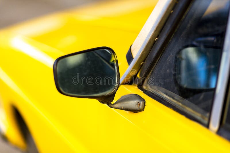 Side mirror details of an antique yellow car in Turkey