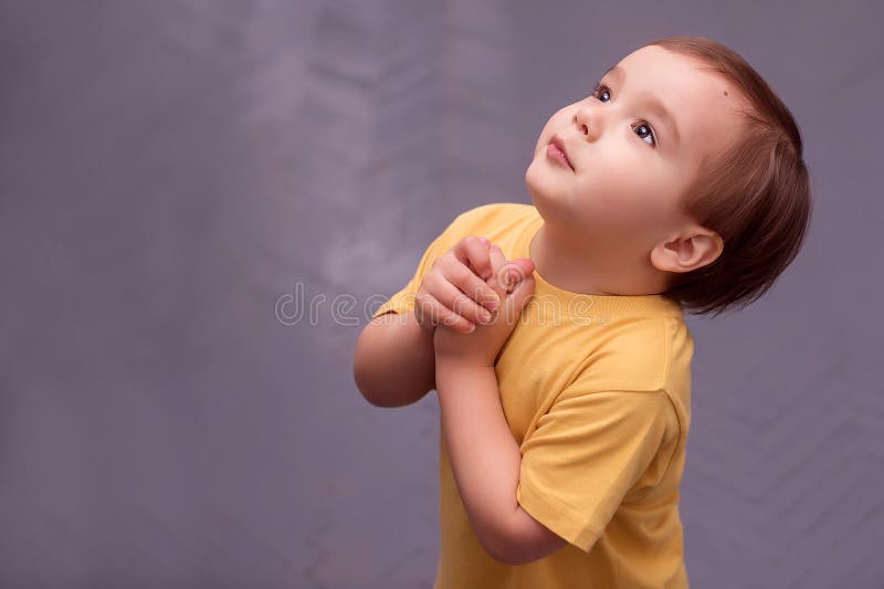 Side portrait of a little boy begging or asking for something against grey painted floor royalty free stock image Side portrait of a little boy begging or asking for something against grey painted floor royalty free stock image
