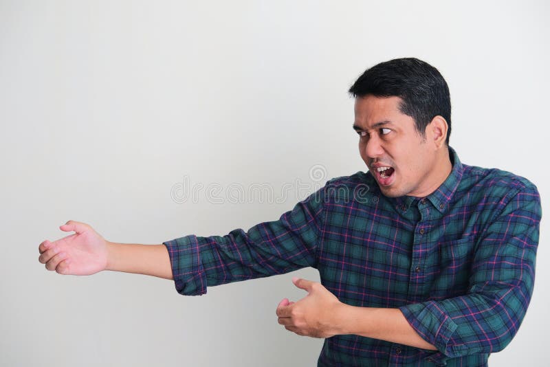 Side view of adult Asian man doing rope pull pose with serious face expression stock image