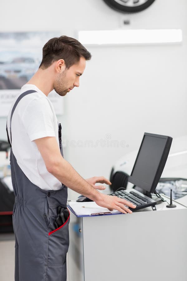 Side View of Automobile Mechanic Using Computer in Stock Photo