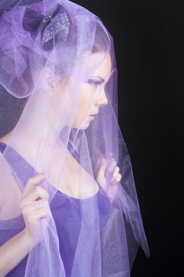 Side-view of beautiful young woman in violet hat