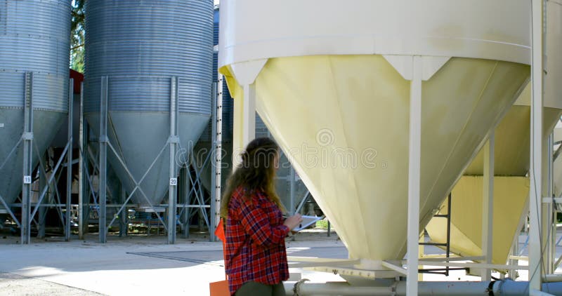Side view of caucasian female worker looking at storage tanks working on digital tablet 4k