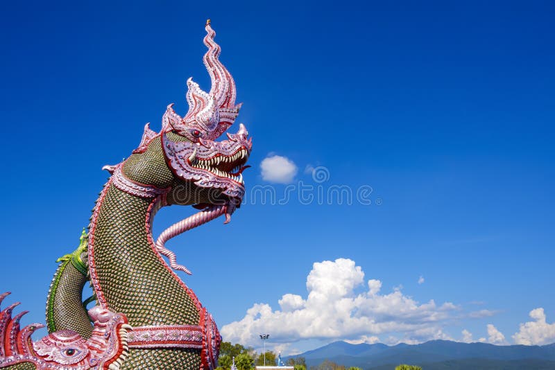 Side view of colorful traditional serpent statues on bannister of Thai temple against cloud on blue sky with beautiful rural scene stock images