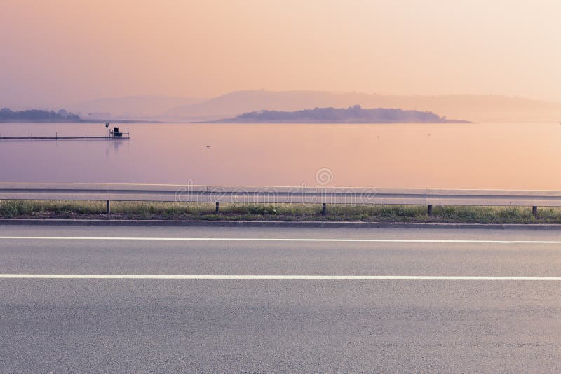 Side view of empty asphalt road and lake stock image