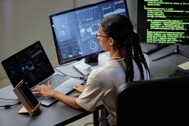 Female Programmer Coding on Laptop at Professional Workstation with Computers in Office royalty free stock images