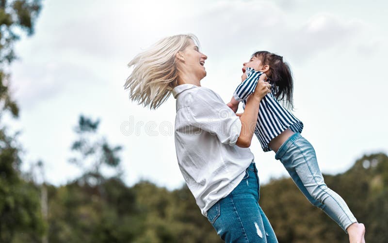 Side view image of happy little daughter playing with her smiling mother in the park. Loving woman and her little kid girl stock image Side view image of happy little daughter playing with her smiling mother in the park. Loving woman and her little kid girl stock image