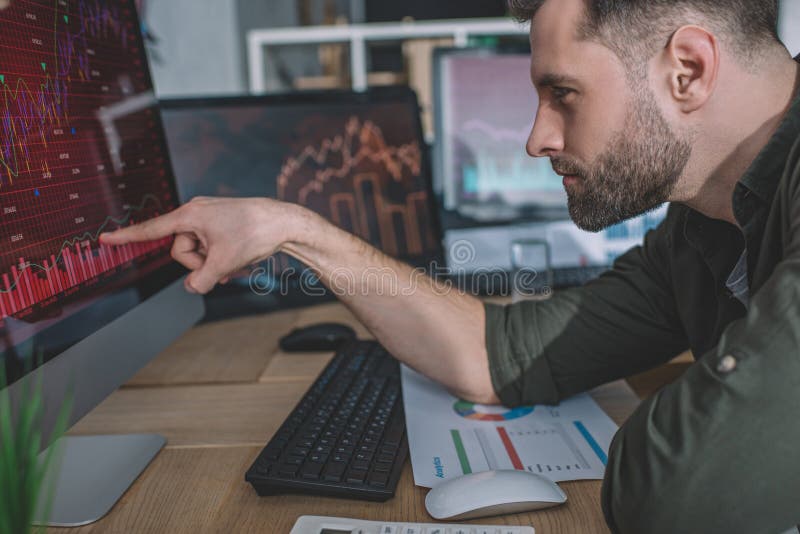 Side view of information security analyst pointing with finger on charts on computer monitor while working royalty free stock images