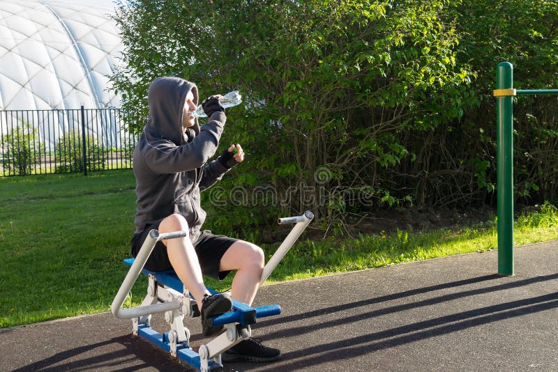 Side view of a man doing abs exercises using a simulator on a sports ground on a street stock photography Side view of a man doing abs exercises using a simulator on a sports ground on a street stock photography