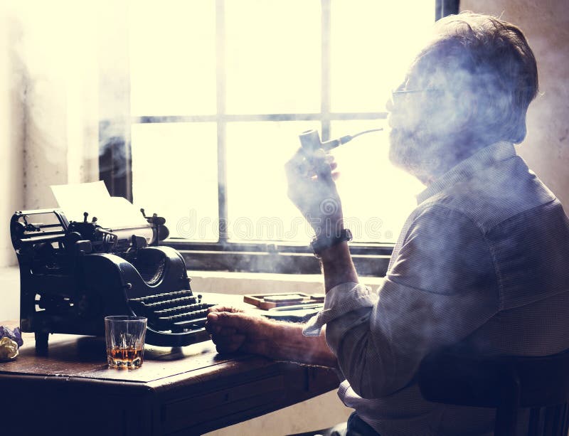 Side View of Man Smoking Pipe while Working on Typewriter Stock Photo