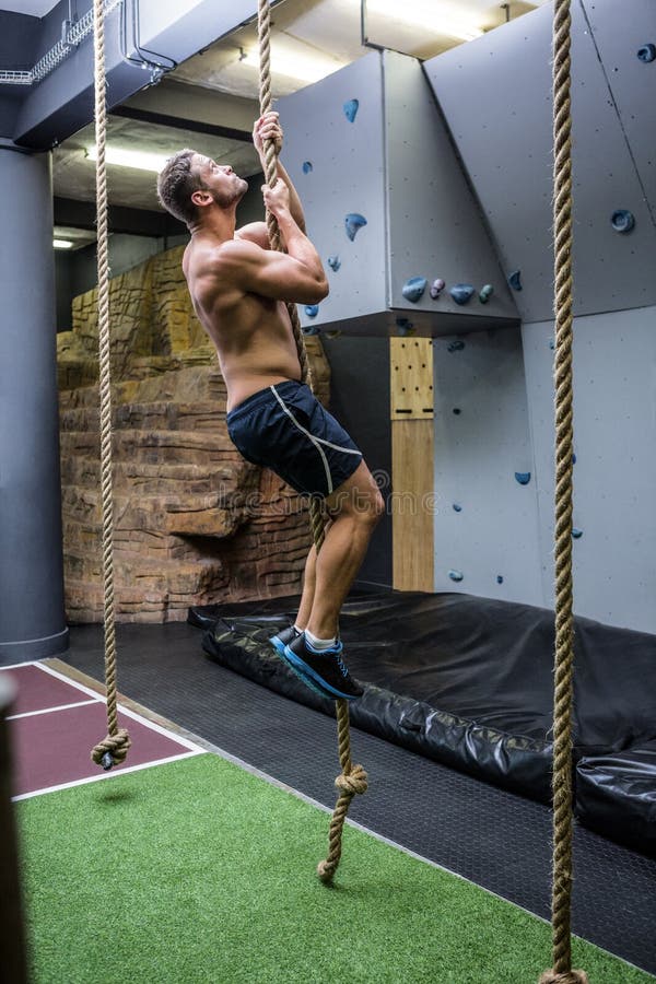 Side view of muscular man doing rope climbing stock images