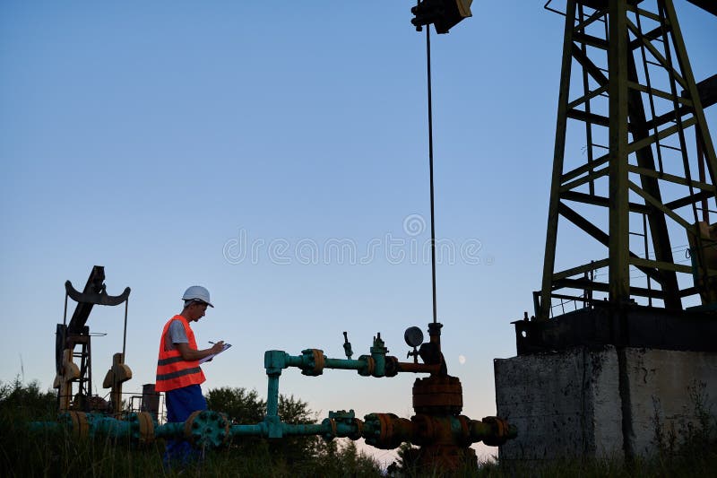 Mechanic Recording Performance of Operation Pump Jack. Stock Photo