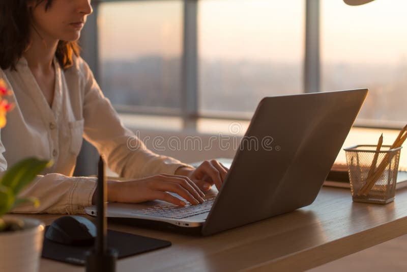 Side view photo of a female programmer using laptop, working, typing, surfing the internet at workplace. royalty free stock images