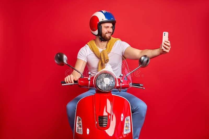 Side view on young pleasant caucasian man taking photo of himself with bike, male in casual wear use smartphone on road, while driving. Side view on young pleasant caucasian man taking photo of himself with bike, male in casual wear use smartphone on road, while driving