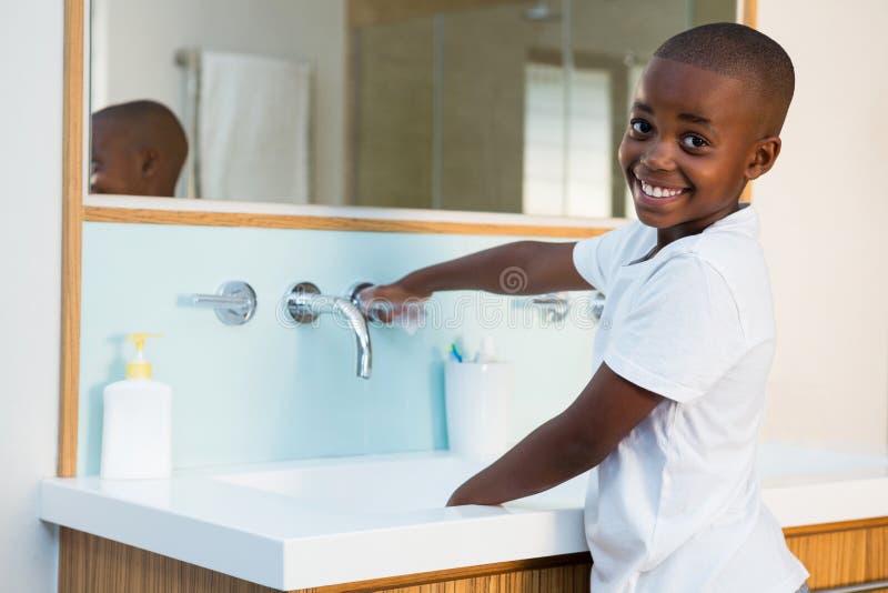 Side view portrait of smiling boy washing hands in sink stock image Side view portrait of smiling boy washing hands in sink stock image