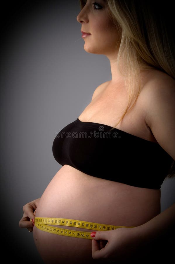 Side view of pregnant female measuring her tummy